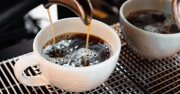 Gorąca kawa spływa do białej filiżanki. Zastanawiasz się, czy kawa podnosi poziom cukru?