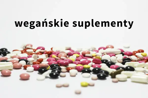 Kolorowe tabletki i kapsułki, w tym suplementacja dla wegan, rozsypane na białym tle.
