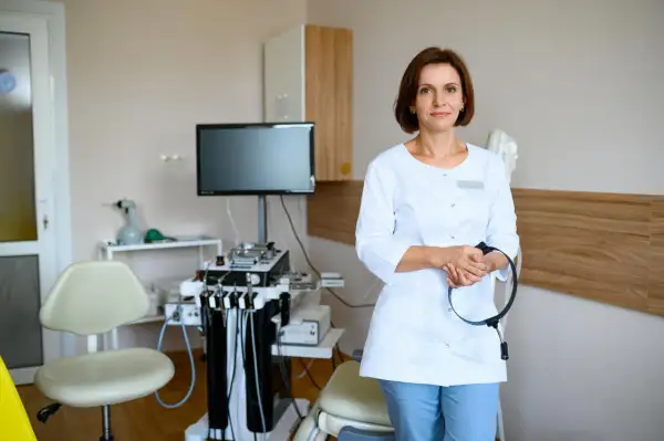 Lekarka w gabinecie foniatrycznym, z aparaturą medyczną w tle. Czy badanie u foniatry jest bolesne? Niekoniecznie, nowoczesny sprzęt i doświadczenie lekarza minimalizują dyskomfort.