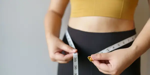 Kobieta mierzy talię centymetrem. Czy to oznaka szybkiego metabolizmu?