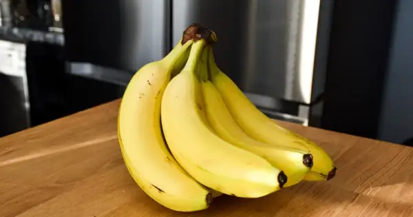Pęk żółtych bananów na drewnianym blacie. Czy banany a niedoczynność tarczycy to dobry duet?
