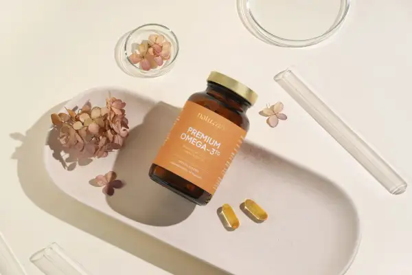 Butelka z napisem "PREMIUM OMEGA-3TG" i dwie kapsułki. Idealne wsparcie dla rozwoju mózgu i serca w ciąży.